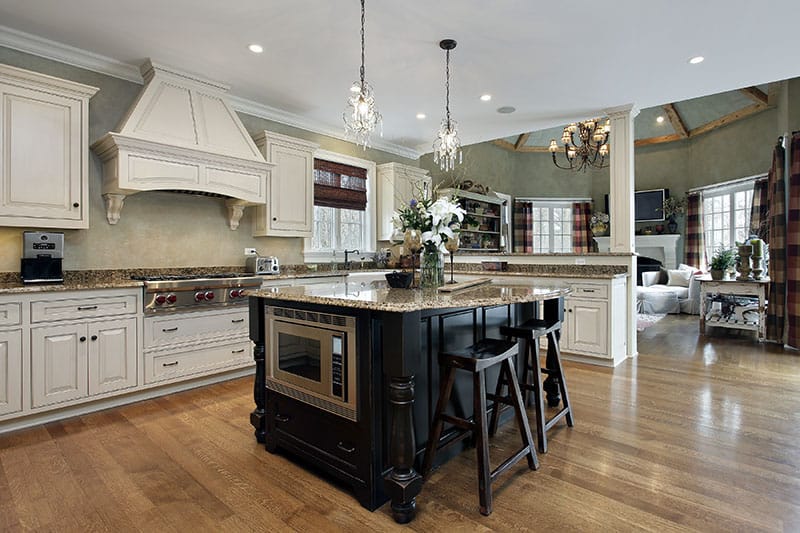 Marble Countertop Island With Black Wooden Cabinetry In An Open Ended Luxurious Kitchen