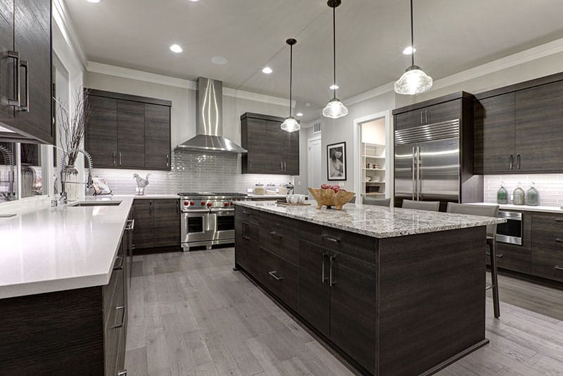 Modern Gray Kitchen Features An Island With Dark Gray Flat Front Cabinets Paired With White Quartz Countertops And A Glossy Gray Linear Tile Backsplash