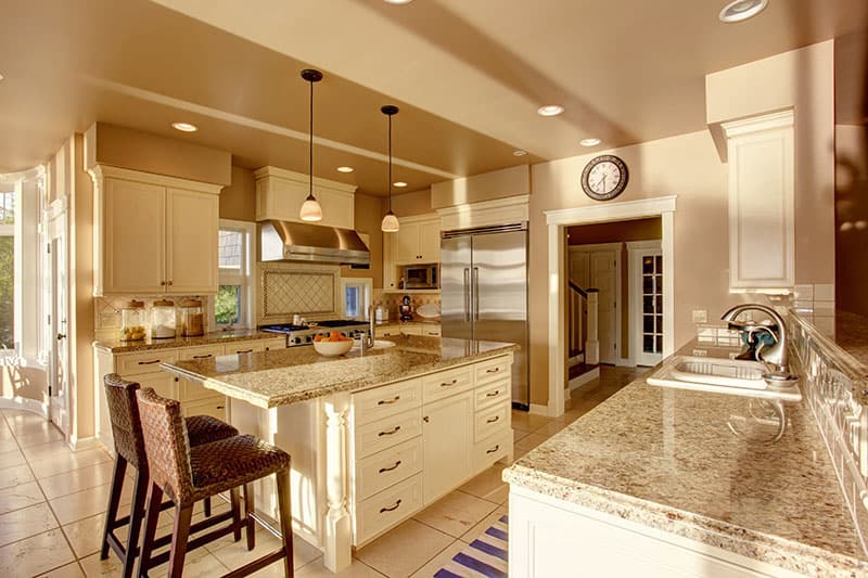 Island With Beige Countertops And White Cabinets In A Luxurious Kitchen